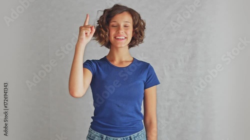 Enlightened adorable youth female with raised finger having brilliant idea showing creative inspiration, studio isolated white background