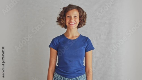 Beautiful smart student gifting perfect smile to camera showing genuine warmth and friendliness, studio isolated white background