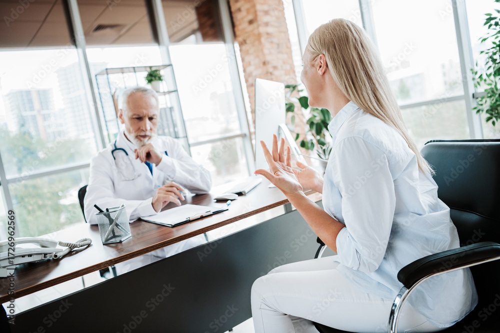 Fototapeta premium Consultation in a modern medical office with doctor listening intently to patient concerns and noting details for diagnosis