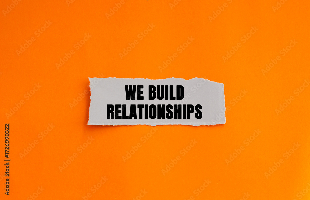 Naklejka premium We Build Relationships message written on ripped torn white paper piece on orange background. Conceptual We Build Relationships symbol. Copy space.