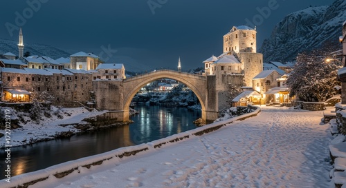 Snowy european cityscape at night with ancient stone bridge