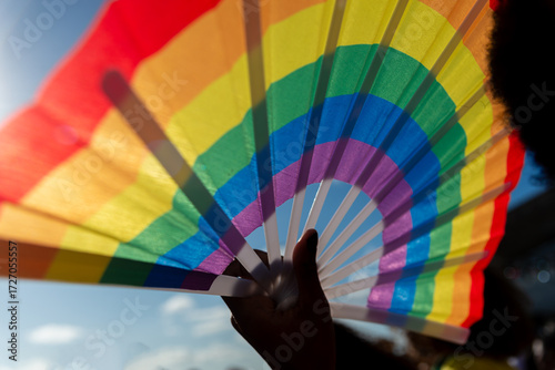 A person holds a fan in the colors of the LGBT flag during a demonstration at Farol da Barra in Salvador, Bahia.