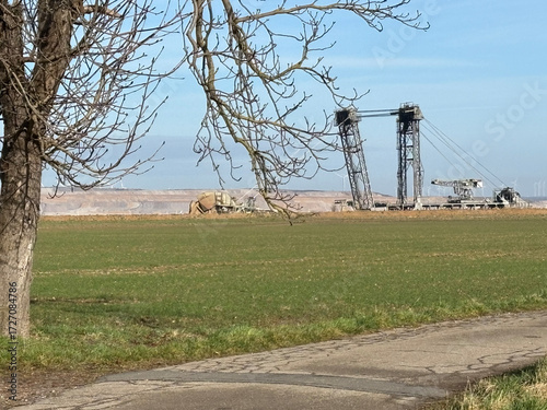 RWE lignite excavator on the edge of the Hambach opencast mine. Chestnut tree and field in the foreground. Exit of Bürgewald (formerly Morschenich), Germany, Europe, on February 25, 2025