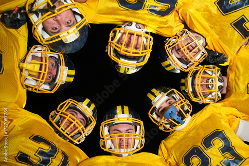 Photography American football team members in yellow jerseys and helmets huddling together