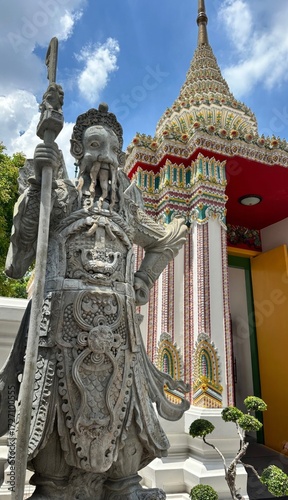 Slika na platnu Stone guardian statue stands resolute beside ornate pagoda, embracing spiritual