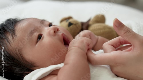 Mother uses the white towel clean her baby mouth from feeding milk.