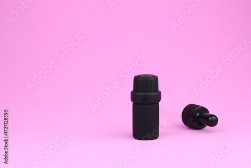 black color essential oil bottle is on pink table with a dropper , fragrance bottle is used with humidifier to create relax and cozy ambient in bedroom on Valentine day , air freshener aroma diffuser
