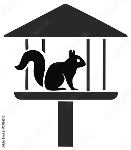Black silhouette of a squirrel sitting on a bird feeder pole under a roof