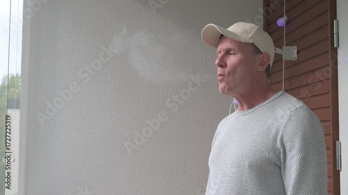Mature man smoking mini cigar outdoors in balcony