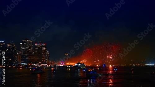 Beautiful celebration of the Independence Day in New York, USA. Fireworks flashing over the East River at night. Numerous boats stand watching the show.