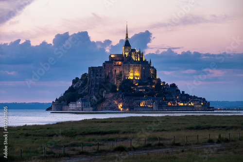 Mont Saint-Michel illuminated at dusk, rising majestically above the bay with dramatic skies and historic architecture, symbol of France’s heritage and timeless beauty