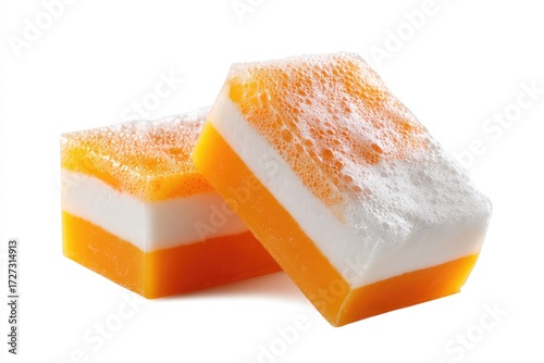Two vibrant orange and white layered soap bars, slightly angled, with a foamy texture, are shown against a stark white background.  The soaps appear moist and ready for use