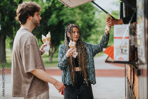 Fotografi A group of friends purchasing and savoring ice cream outdoors surrounded by greenery and sunlight