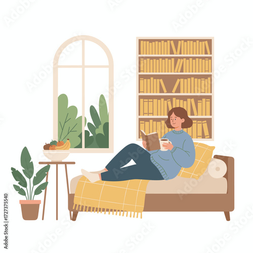 The concept of staying at home: a young woman sits by the window in her living room, relaxing while reading a book and sipping coffee or tea