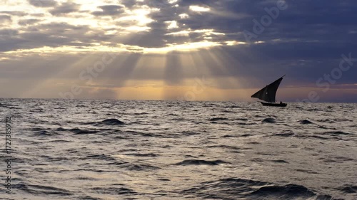 A traditional Swahili Dhow sailing off the coast of Zanzibar in the Indian Ocean during sunrise. 4k slow motion video.