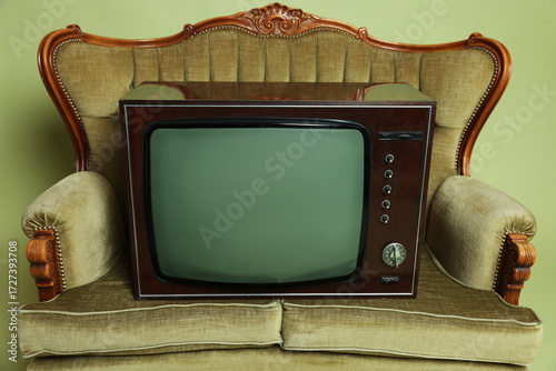 Retro TV set and sofa on olive background, closeup. Used stuff