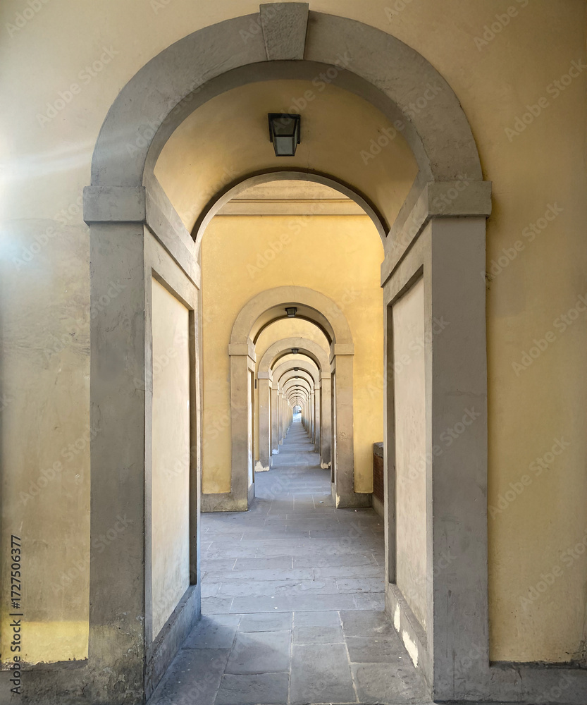 Fototapeta premium Symmetrical yellow archways forming tunnel in Florence