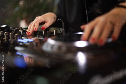 Mãos femininas operando equipamento de DJ durante apresentação musical, destacando tecnologia, ritmo e performance ao vivo.