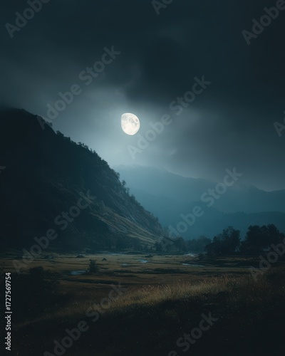 Full moon rising over valley landscape at night; dramatic moonlight shines on mountain and meadow; atmospheric scene in nature; vertical composition