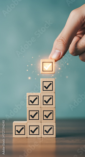 Completing tasks and achieving goals, a hand places the final checkmark on a stack of wooden blocks representing success and progress in business or personal development