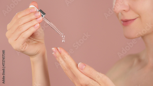 Photos Woman applying cosmetic serum with dropper onto hand