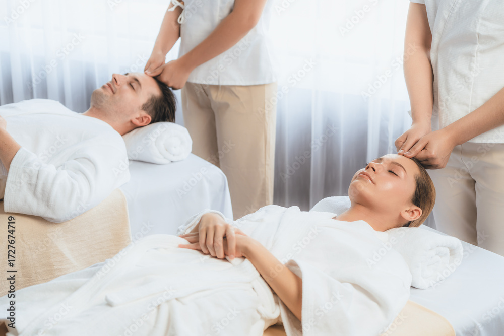Obraz premium Caucasian couple enjoying relaxing anti-stress head massage and pampering facial beauty skin recreation leisure in dayspa modern light ambient at luxury resort or hotel spa salon. Quiescent