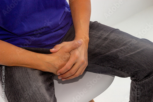 An adult man sits and appears to be covering his groin with his hands. Potency concept, impotence, male strength. urinary problems in men