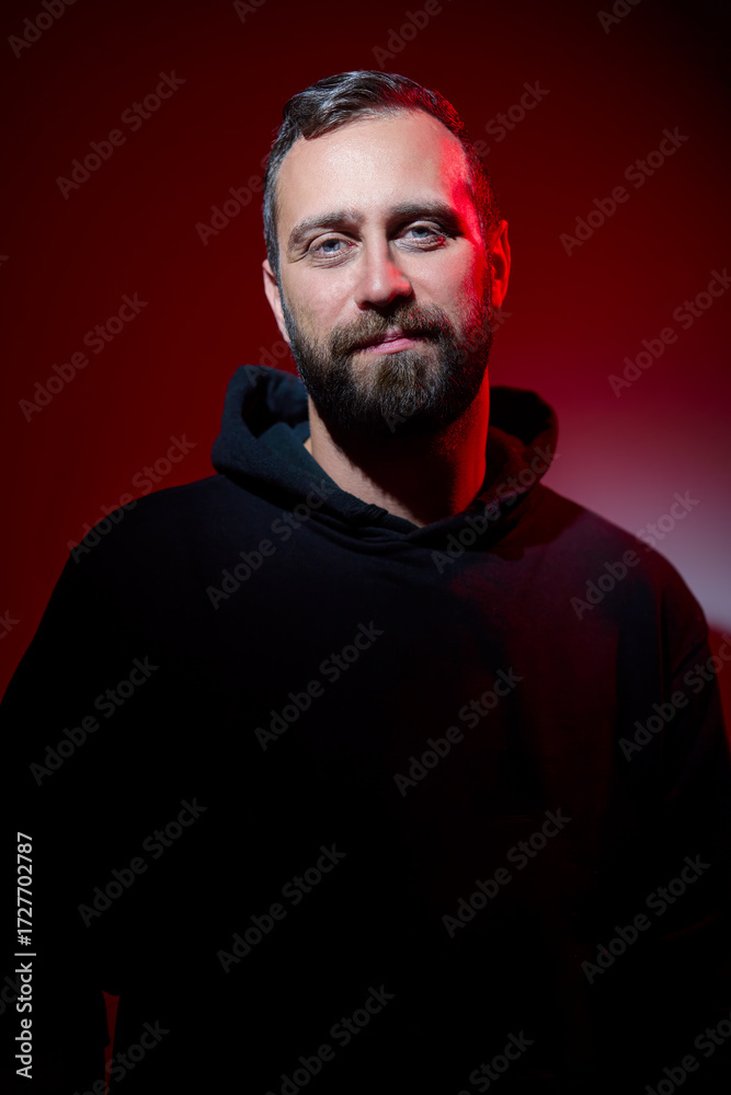Fototapeta premium Portrait Of a Bearded Man Against Red Background with Dramatic Lighting