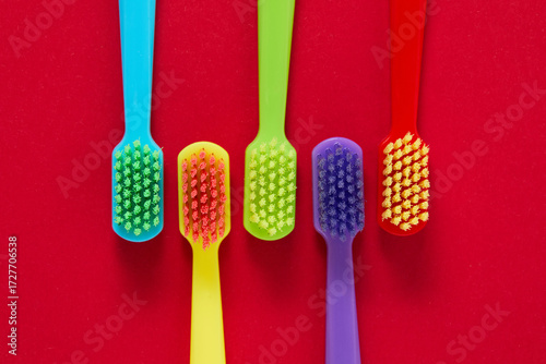Four colorful toothbrushes are arranged on a vibrant red background, emphasizing oral hygiene and dental care