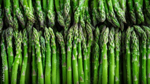 Close-up view of fresh, vibrant green asparagus spears, densely packed and glistening with water droplets.