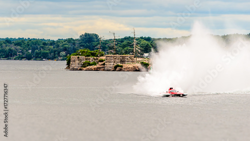 Close view of a red and white racing boating throwing surf during a high speed turn.