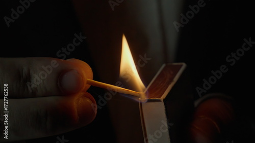 фотографія Unknown person striking match on side of box dark isolated closeup