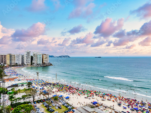 Vista aérea de dia ensolarado com muitos turistas na Praia de Pitangueiras no litoral paulista, Guarujá. 