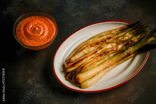 Grilled calçots with romesco sauce on a rustic table