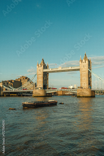 Boat Floating Down River Thames in Front of Tower Bridge in London, England during Summertime Golden Hour