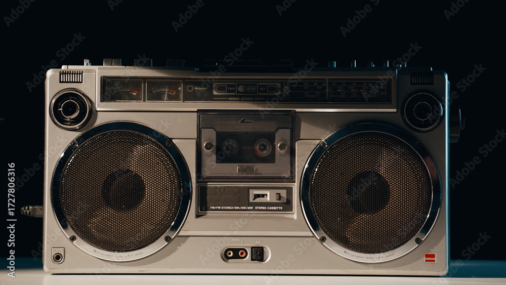 Fototapeta premium Hand pressing button boombox standing in evening light closeup. Listener turning