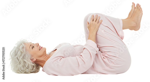 Smiling senior woman in pajamas lying down, knees to chest