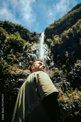 man in the mountains in front of a waterfall
