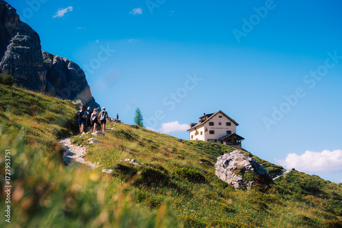 hut on the mountain top with hiker walking towards it