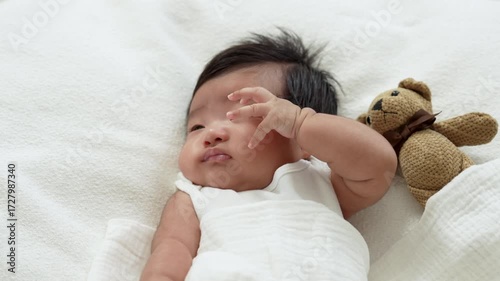 Asian Infant baby laying and yawn on white bed, ready to sleep.