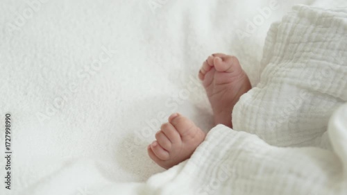 Selected focus on newborn baby feet laying on the white bed.