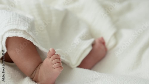 Selected focus on newborn baby feet laying on the white bed.