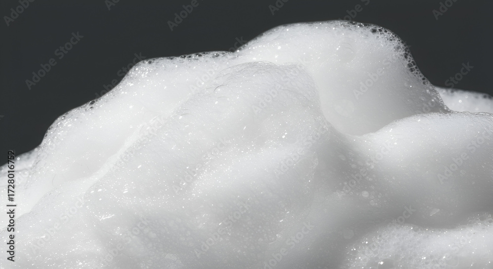 Fototapeta premium Close-up of luxurious white foam with soft bubbles against a dark background
