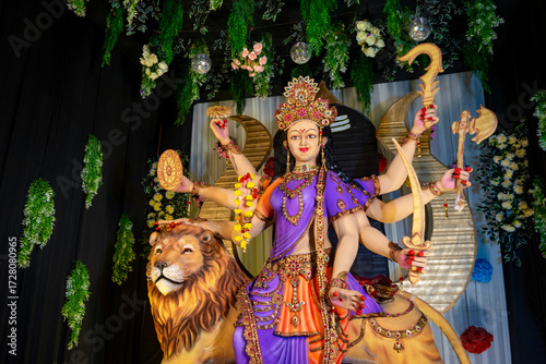 Colorful statue of Goddess Durga with multiple arms holding weapons, seated on a lion