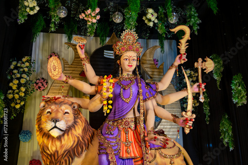 Colorful statue of Goddess Durga with multiple arms holding weapons, seated on a lion