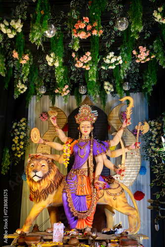 Colorful statue of Goddess Durga with multiple arms holding weapons, seated on a lion