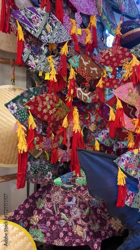 A vibrant collection of colorful batik wau placed against a bamboo frame for sale at the retail.