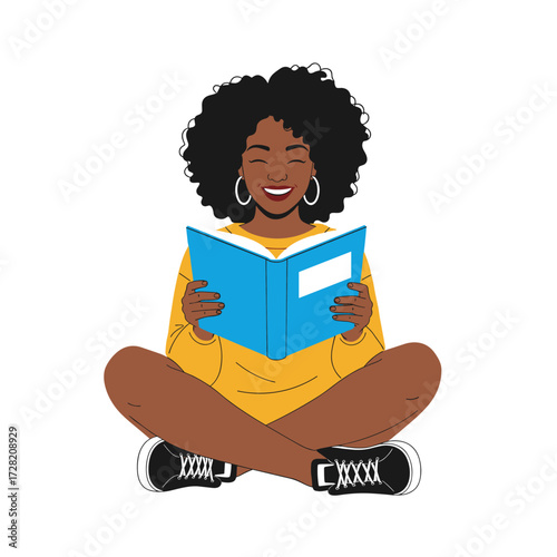 A young Black woman happily reading a book while sitting cross-legged.