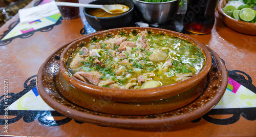 Typical dish from Guadalajara, Jalisco, called CARNE EN SU JUGO, on a handmade clay plate made in Mexico with spicy sauces on the background