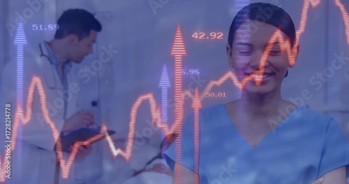 Nurse standing with doctor writing notes while animated vitals graph fading in rising data surge